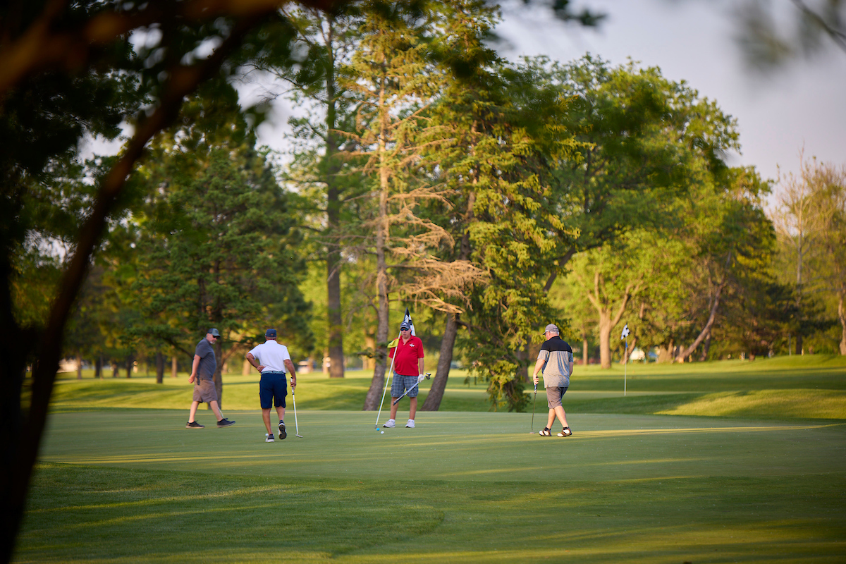 Four golfers discuss strategy on the green.
